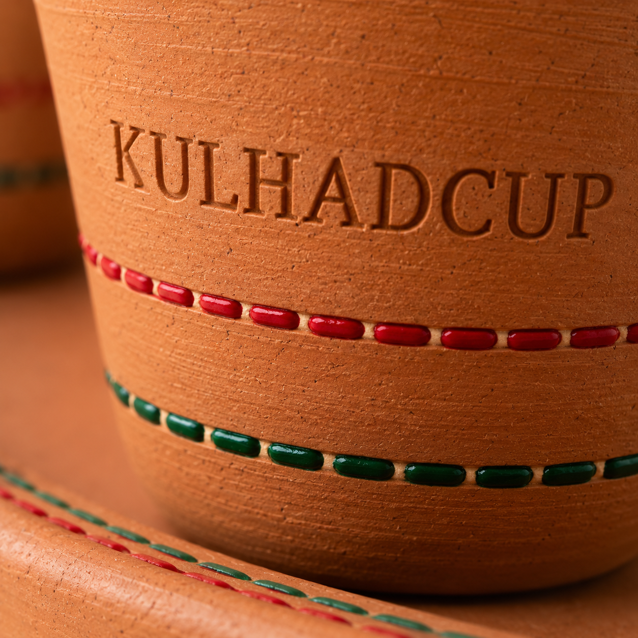 Close-up of engraved KulhadCup kulhads in mustard and indigo on a terracotta tray